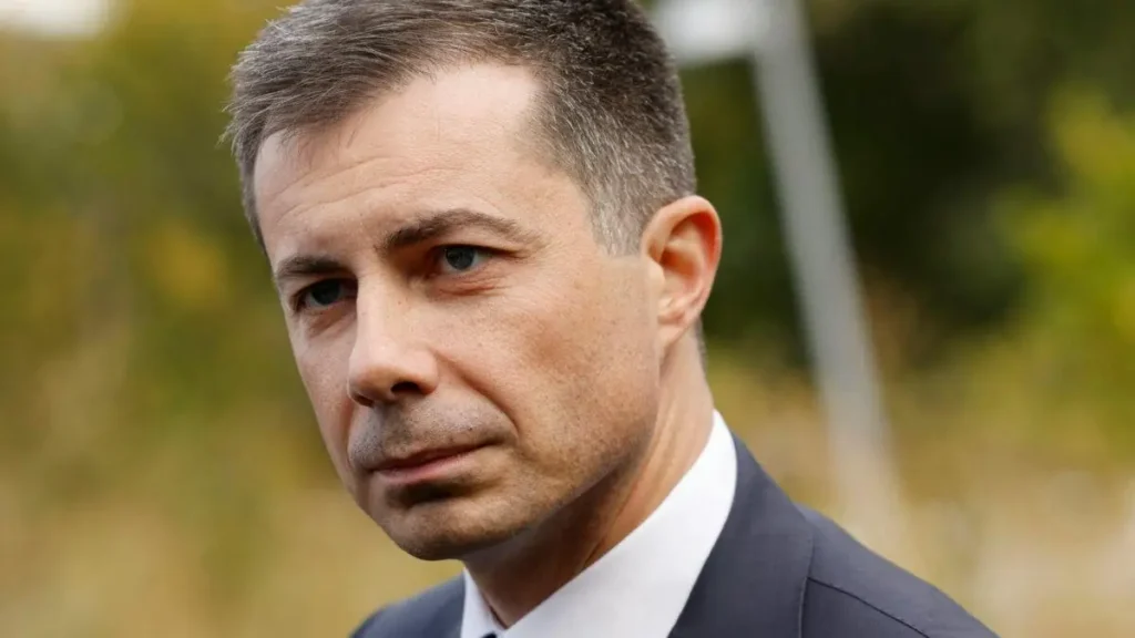 The image shows a man in a suit and tie, looking off to the side with a serious expression.