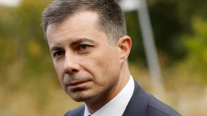 The image shows a man in a suit and tie, looking off to the side with a serious expression.