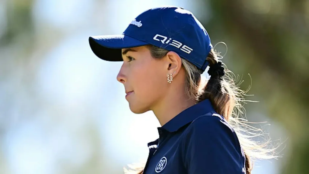 The image shows a golfer wearing a blue cap and uniform, looking focused and ready for a game.