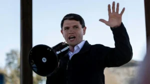A man is speaking passionately into a megaphone while raising his other hand in a gesture of emphasis.
