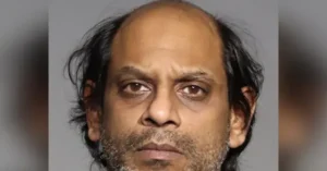 The image appears to be a mugshot of a man with a receding hairline and a beard, taken against a plain background.
