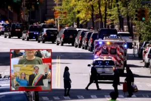 The image shows a busy city street with emergency vehicles and a crowd of people, including one holding a picture of a political figure.