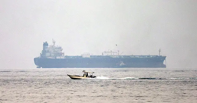 A small motorboat speeds across the water in the foreground, with a large tanker ship visible in the background.