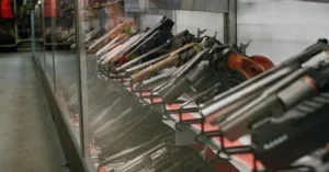 The image shows a display case in a store containing a variety of firearms.