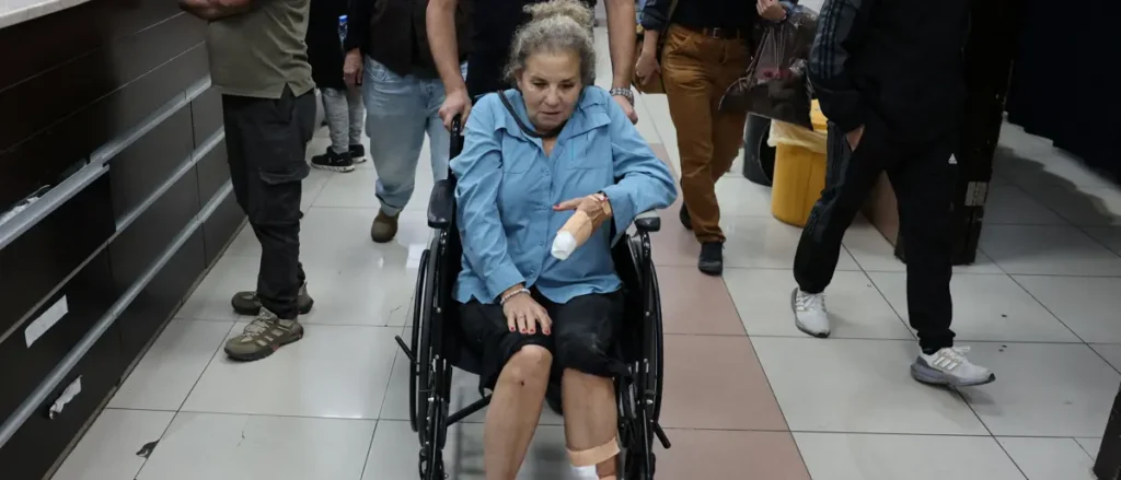 A woman in a wheelchair is being assisted by others in a public space.
