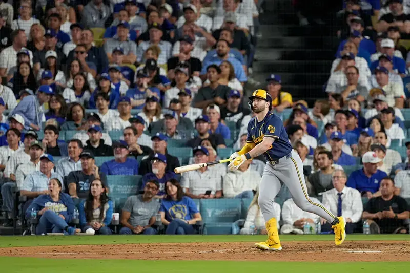 A baseball player swings his bat during a game in front of a large crowd.