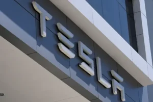 The image shows the Tesla logo prominently displayed on the exterior of a building.