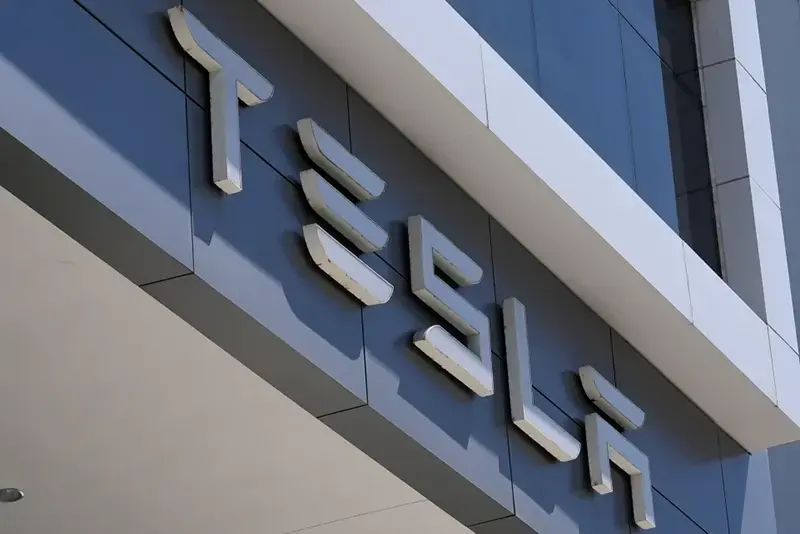 The image shows the Tesla logo prominently displayed on the exterior of a building.