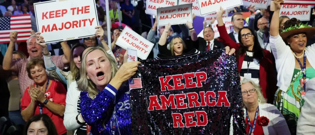 A crowd celebrates with signs and a sequined banner that reads "Keep America Red."