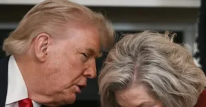The image shows a close-up of two individuals, one with light-colored hair and the other with gray hair, appearing to be engaged in a conversation.