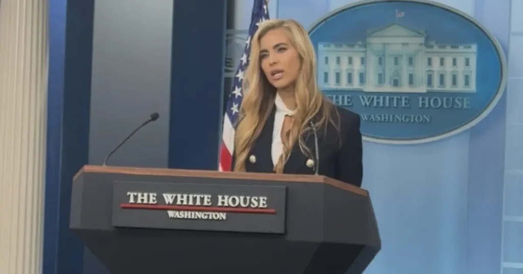 A person stands at a podium labeled "The White House Washington" during a press briefing.
