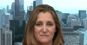 The news photo features a person with long hair in front of a cityscape background.