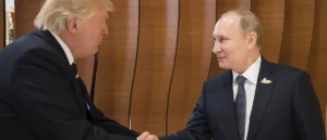The image shows two individuals in formal attire shaking hands in a professional setting.