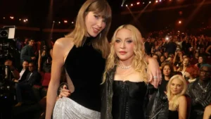 Two celebrities pose together at a glamorous event in front of a cheering audience.