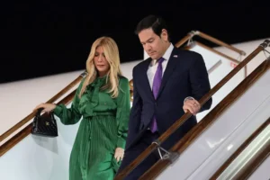 A man and a woman are seen descending the stairs of an aircraft, with the woman holding a small handbag.
