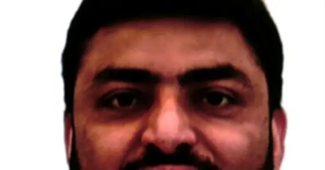 The image shows a close-up of a person with dark hair and a mustache, set against a plain white background.