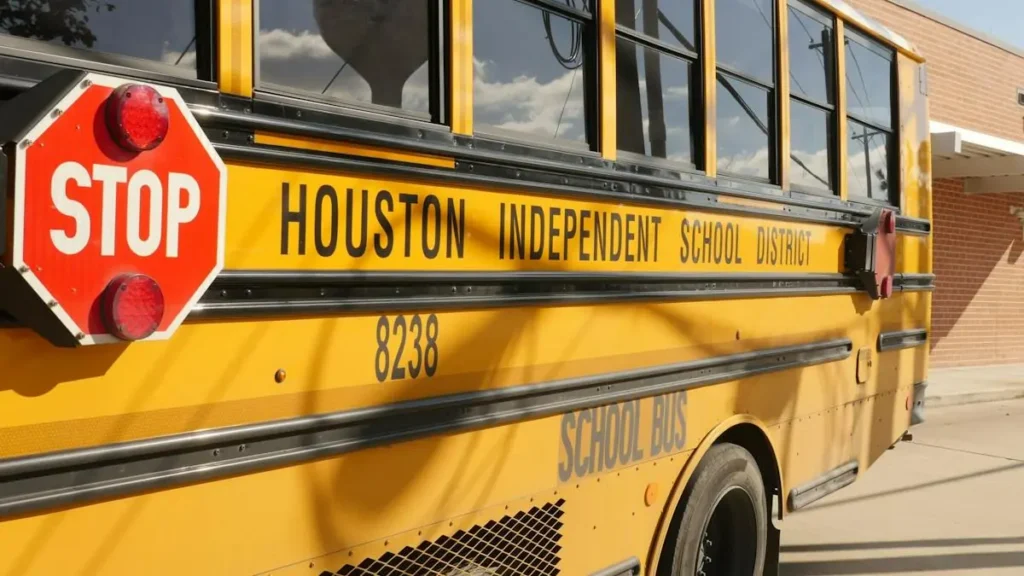 A Houston Independent School District school bus is parked outside a building.