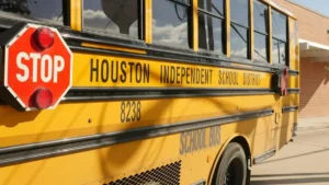 A Houston Independent School District school bus is parked outside a building.