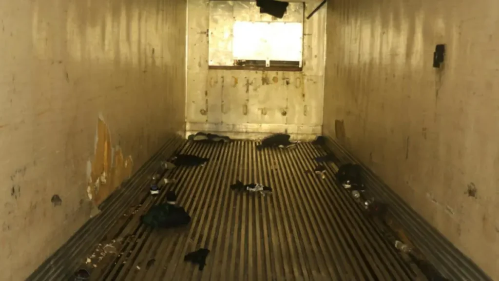 The image shows a dilapidated room with a wooden floor, debris scattered around, and a window letting in light.