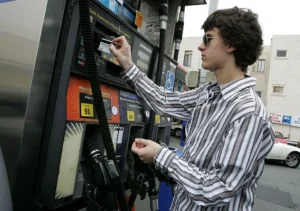 A young man is using a credit card at a gas pump.
