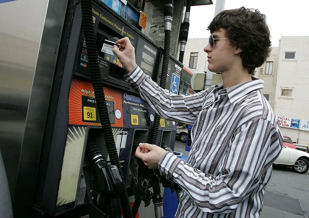 A young man is using a credit card at a gas pump.