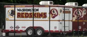 A Washington Redskins-branded truck is parked behind a chain-link fence.