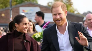 Prince Harry and Meghan Markle are seen smiling and interacting with the crowd during a public engagement.