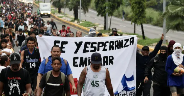 A group of people march down a street holding a banner that reads "FE Y ESPERANZA EMIGRAR," expressing hope and faith amidst migration.