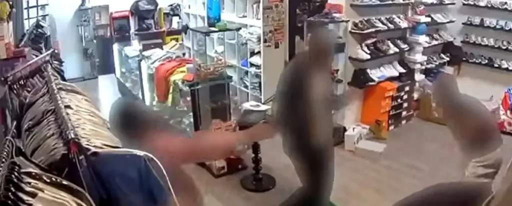 A security camera captures a scene inside a retail store, showing a customer interacting with a cashier at the checkout counter.