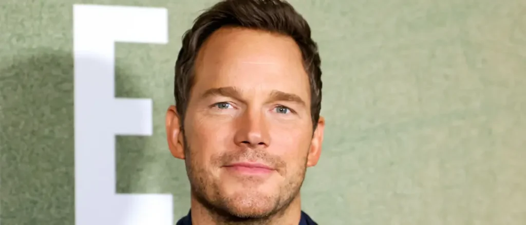 The image shows a man with short brown hair and a light beard, smiling slightly, in front of a green background with a large white letter "F".