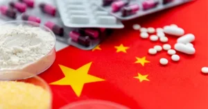 The image depicts a Chinese flag with various pharmaceutical products, including capsules and powders, suggesting a focus on the country's pharmaceutical industry or healthcare sector.