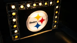 The image shows a brightly lit Steelers logo surrounded by spotlights, likely indicating a pre-game or event setup.