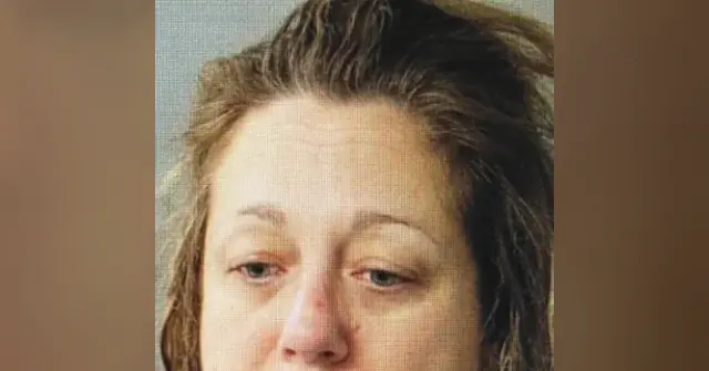 The image appears to be a mugshot of a person with wet hair, captured in a formal setting.