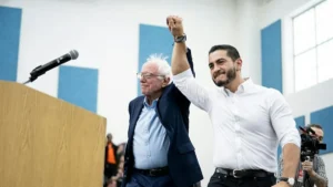 Two individuals raise their hands in solidarity at a public event.