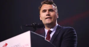 A man in a suit and tie is speaking at a podium during a formal event.