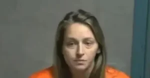 The image shows a person in an orange jumpsuit, likely in a law enforcement or correctional setting.