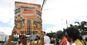 A protestor holds a sign advocating for "60 Reasons to Apologize and Reparations" in Jamaica.