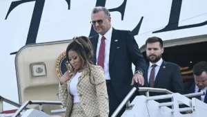 A group of individuals, including a woman in a patterned coat, disembarks from a presidential aircraft.