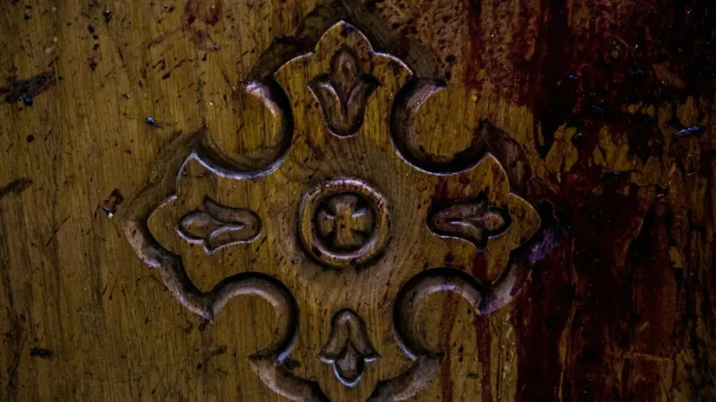 The image shows a close-up of an intricately carved wooden panel with a symmetrical design featuring floral and geometric patterns.