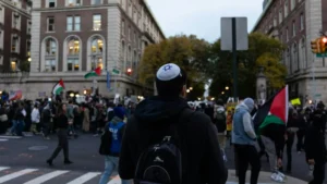 A person wearing a kippah and backpack walks through a crowded street scene with protesters holding Palestinian flags.