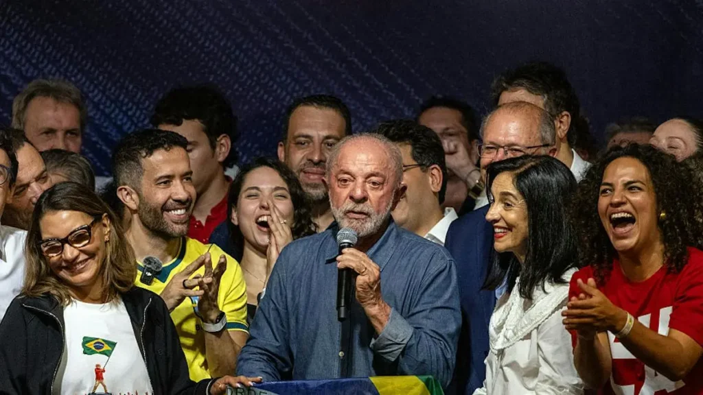 A group of people, including a man speaking into a microphone, celebrate together in a joyful and festive atmosphere.