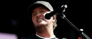A person wearing a cap is singing into a microphone on stage.