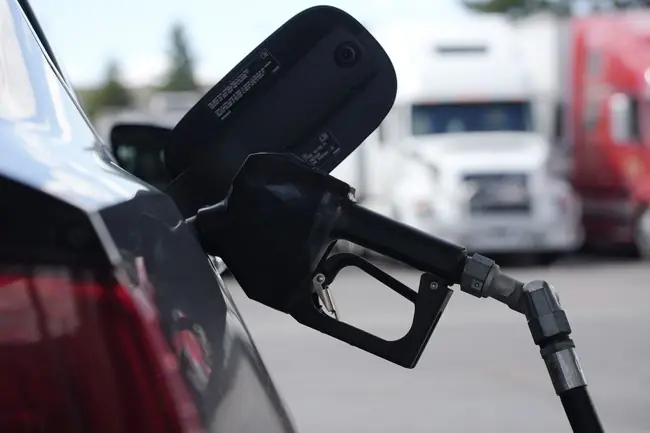 A fuel nozzle is inserted into the fuel tank of a car at a gas station.