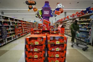 A Halloween-themed candy display is set up in a grocery store aisle, featuring various Hershey's and Reese's products.