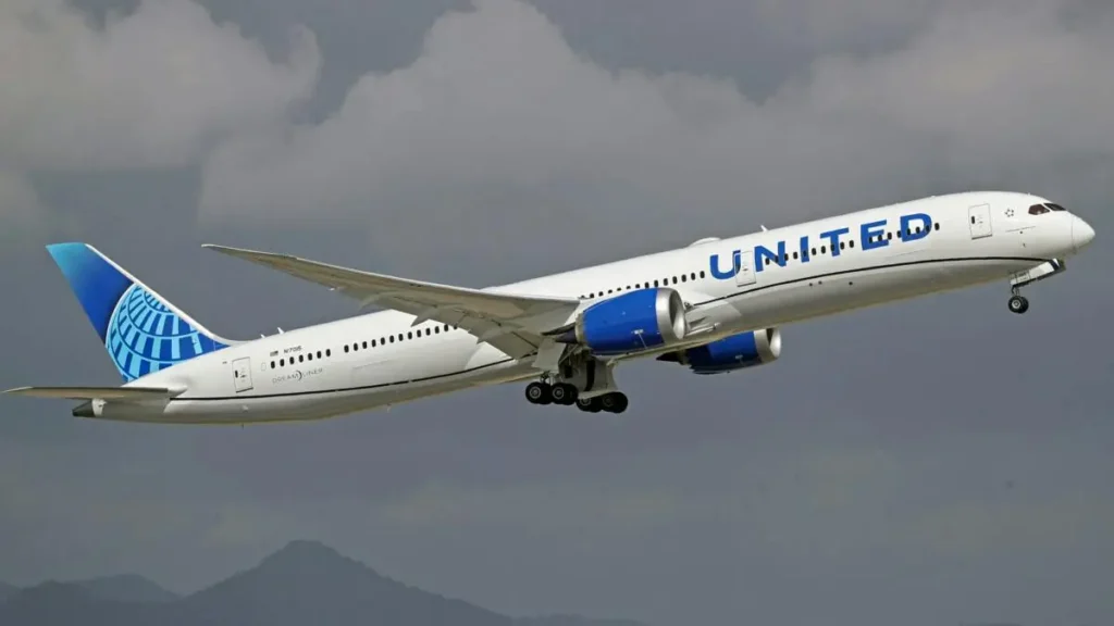 A United Airlines Boeing 787 Dreamliner is captured in flight against a cloudy sky.
