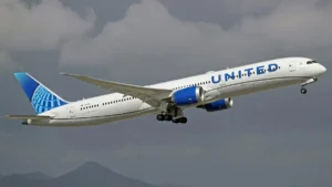 A United Airlines Boeing 787 Dreamliner is captured in flight against a cloudy sky.