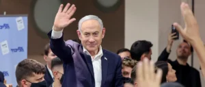 The image shows a man waving to a crowd of people, with some individuals raising their hands, suggesting a public event or gathering.