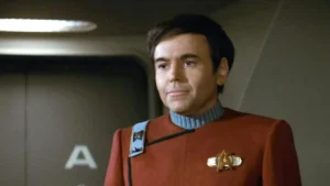 The image depicts a person in a red Starfleet uniform from the Star Trek series, standing in what appears to be a spaceship interior.
