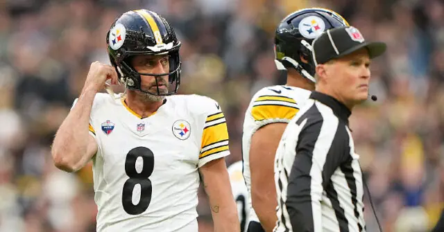 The image shows a football player in a Pittsburgh Steelers uniform interacting with a referee during a game.