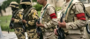 A group of soldiers in camouflage uniforms and armed with rifles are standing in formation.